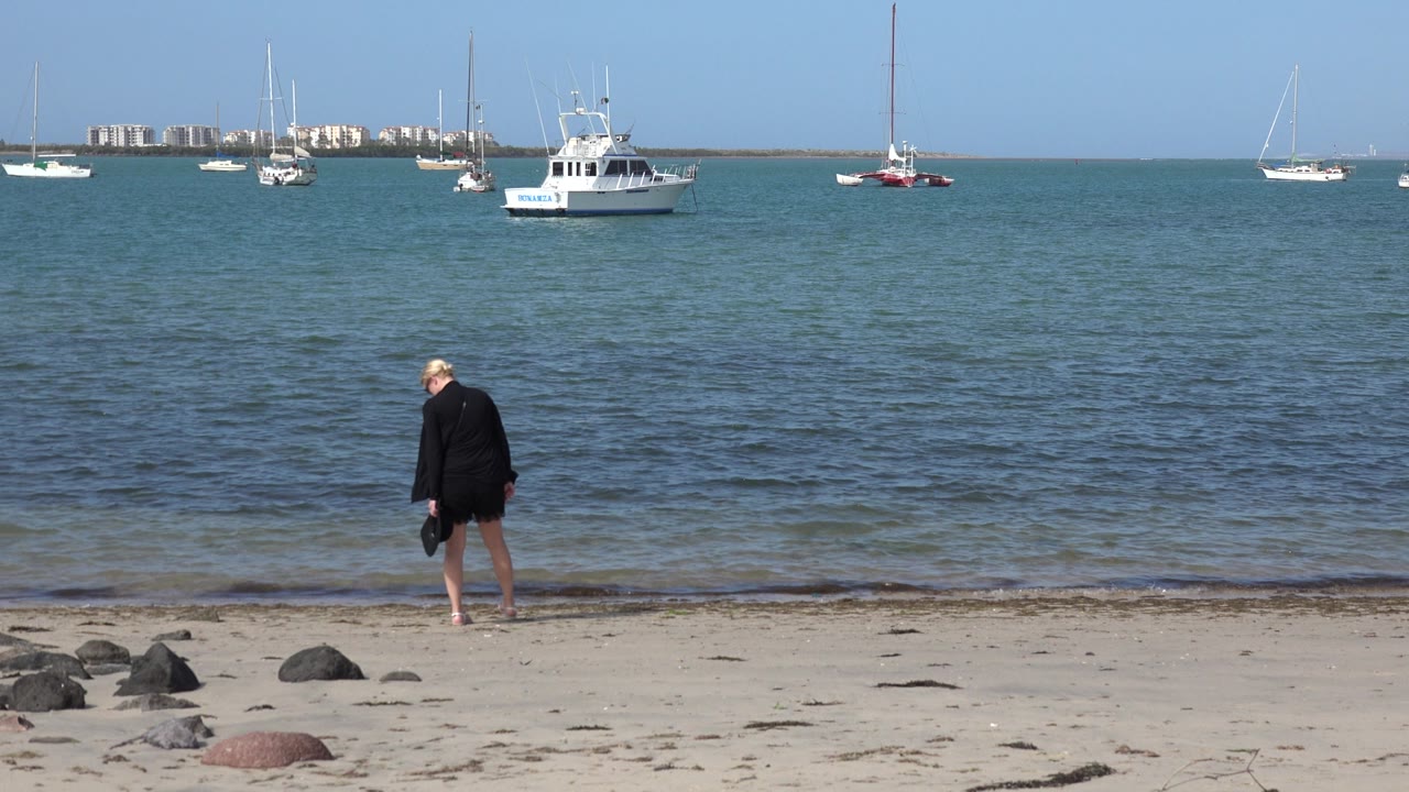At 0:01 in Los Cabos, Mexico, the person remains close to the water with their head angled down as a low wave reaches the sand.