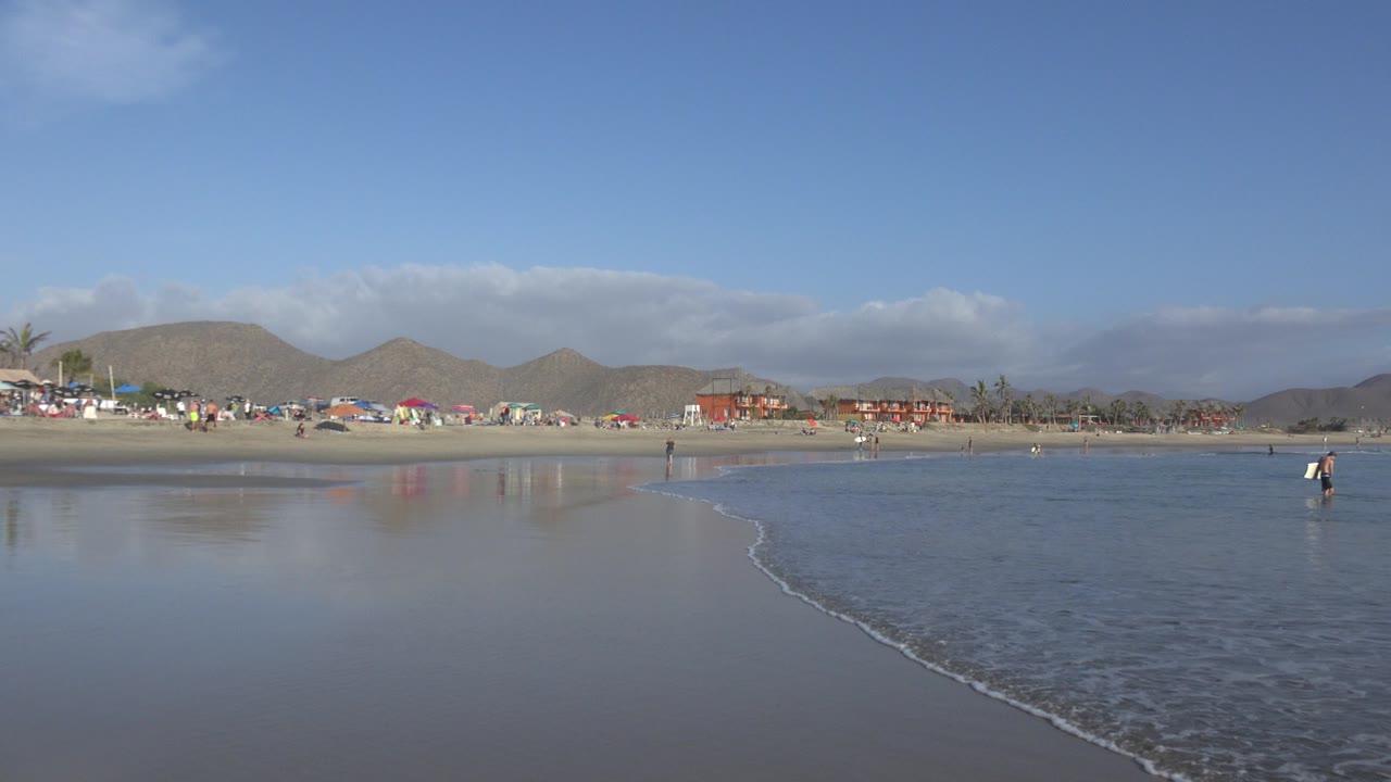 Wide low-tide beach with shallow water and distant people