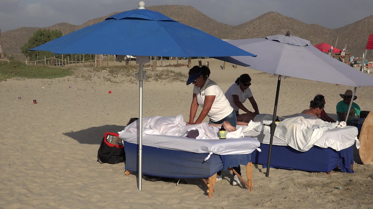 Beach massage tables under umbrellas on sand