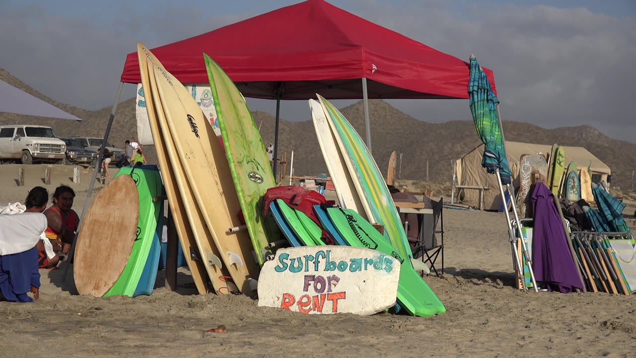Colorful surfboards and beach gear beside a red canopy