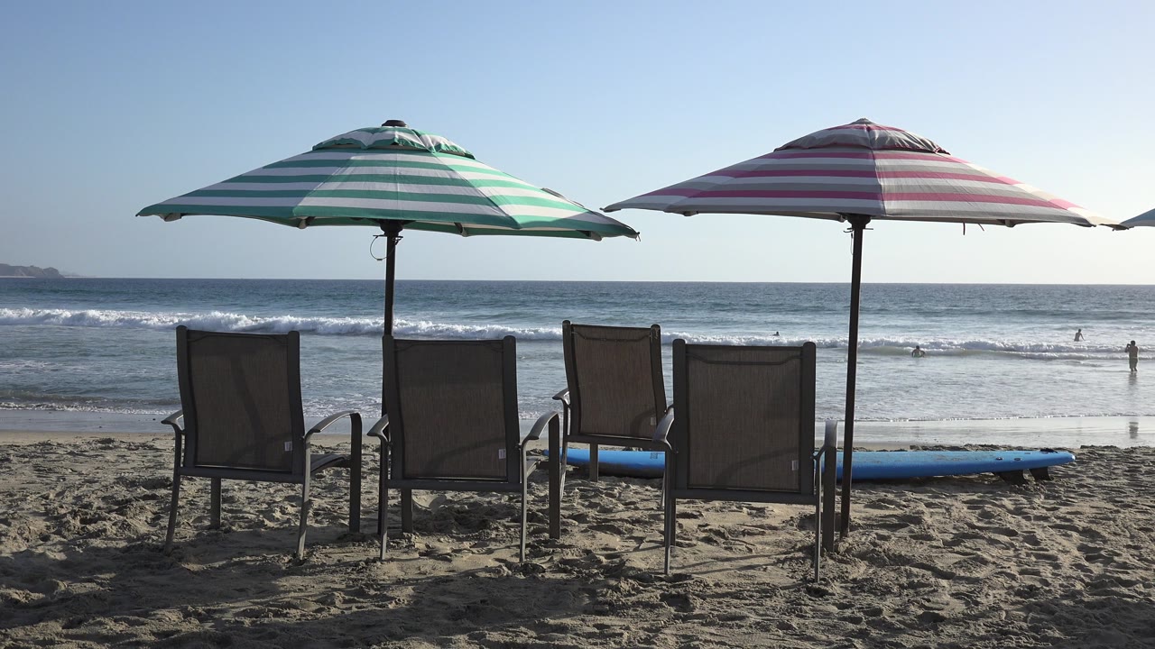 Beach chairs under striped umbrellas facing the ocean