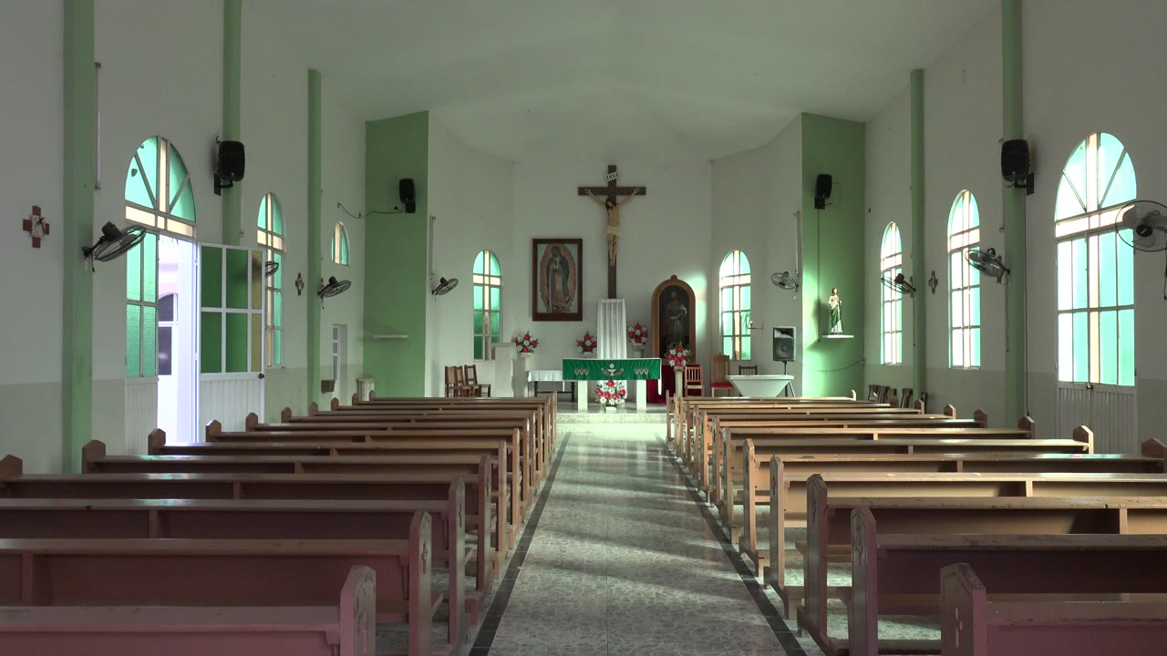 Empty church interior with pews facing an altar and crucifix