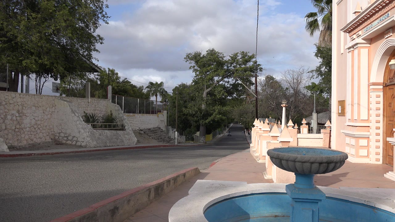Quiet road beside a blue fountain and peach building edge