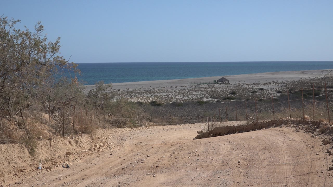 Desert road edge overlooking beach and sea