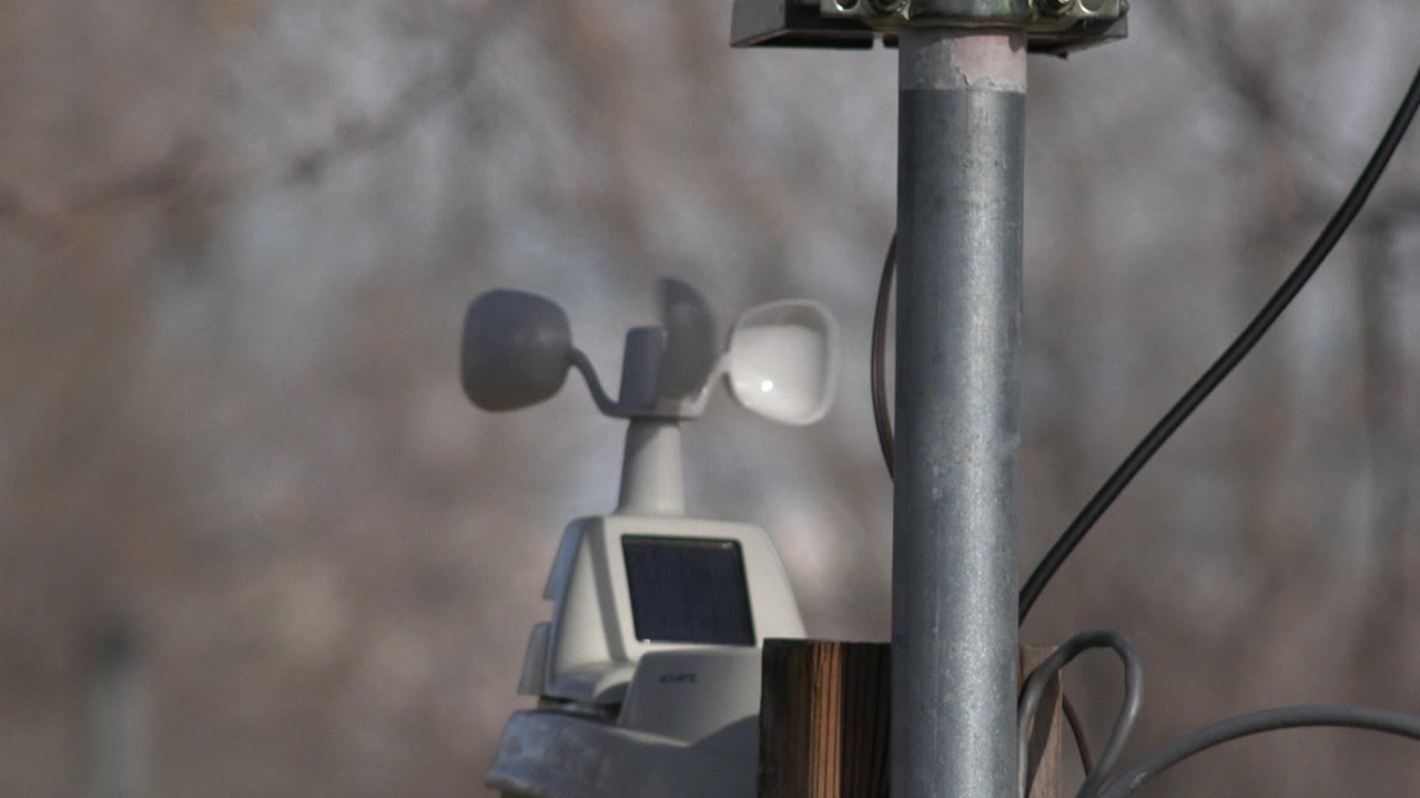 Wind sensor cups and solar panel near a vertical pole.