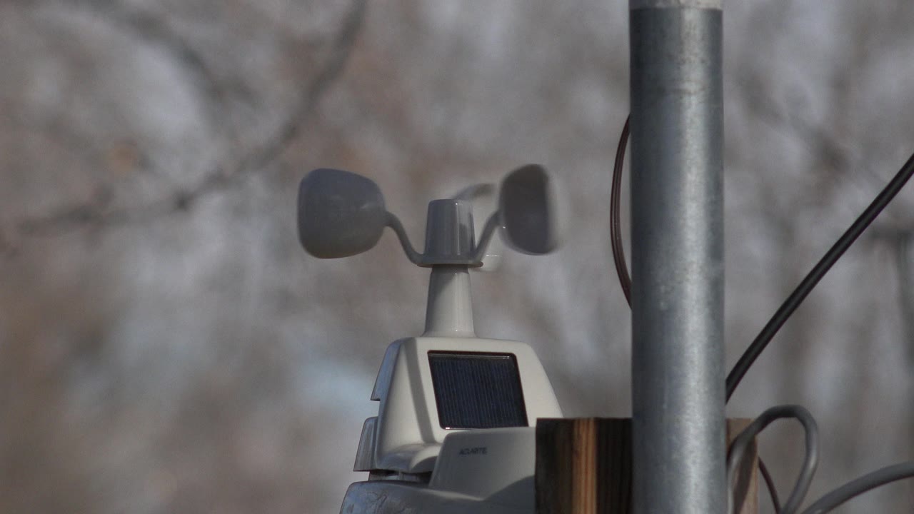 Close view of a wind-measuring device partly aligned with a metal pole.