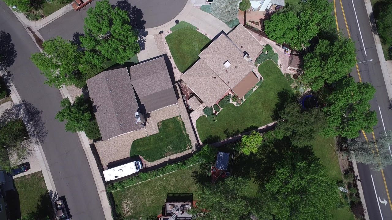 Overhead view of houses, lawns, streets, trees, and a white RV.