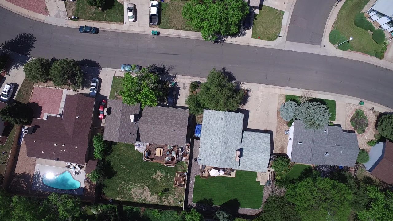 Overhead view of houses, trees, street, and backyard pool
