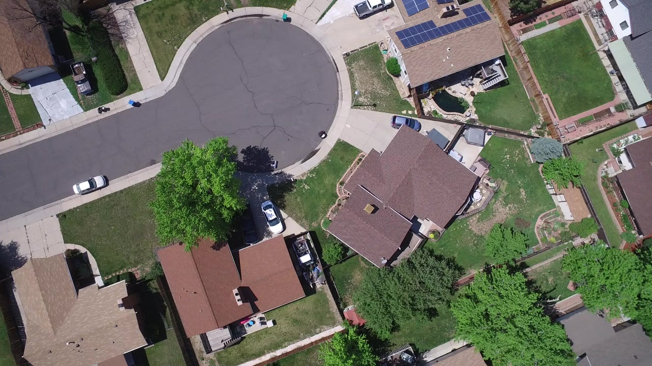 Top-down drone frame over Westminster, Colorado houses beside a cul-de-sac, with green lawns, driveways, parked cars, sidewalks, and no visible people.