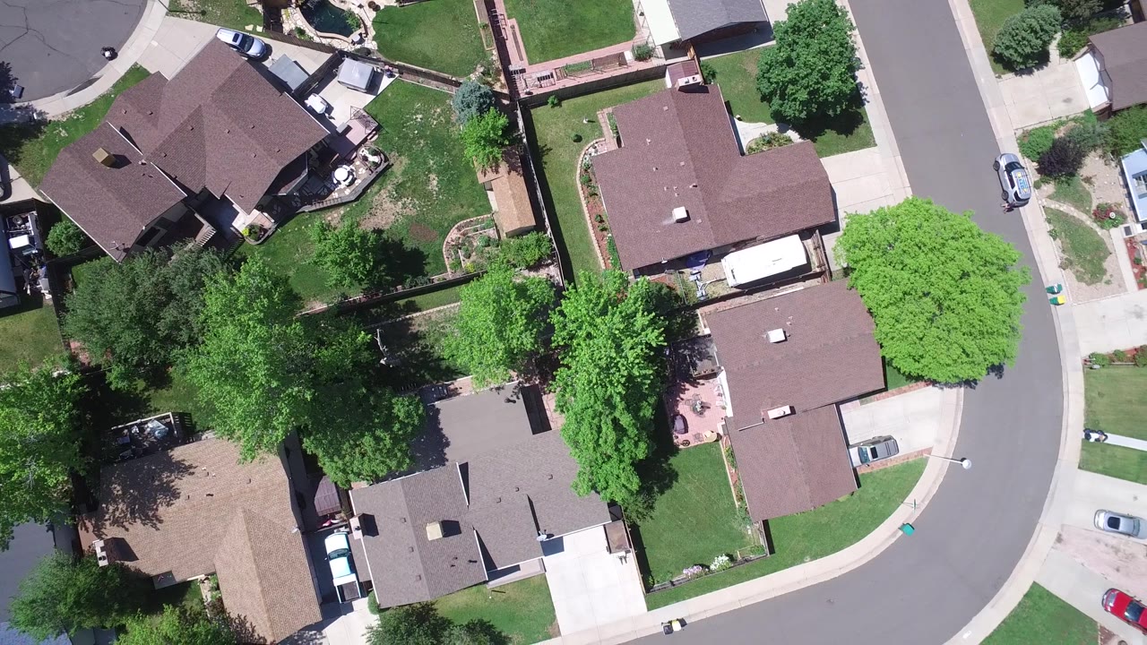 Top-down neighborhood view with houses around a broad curved road.
