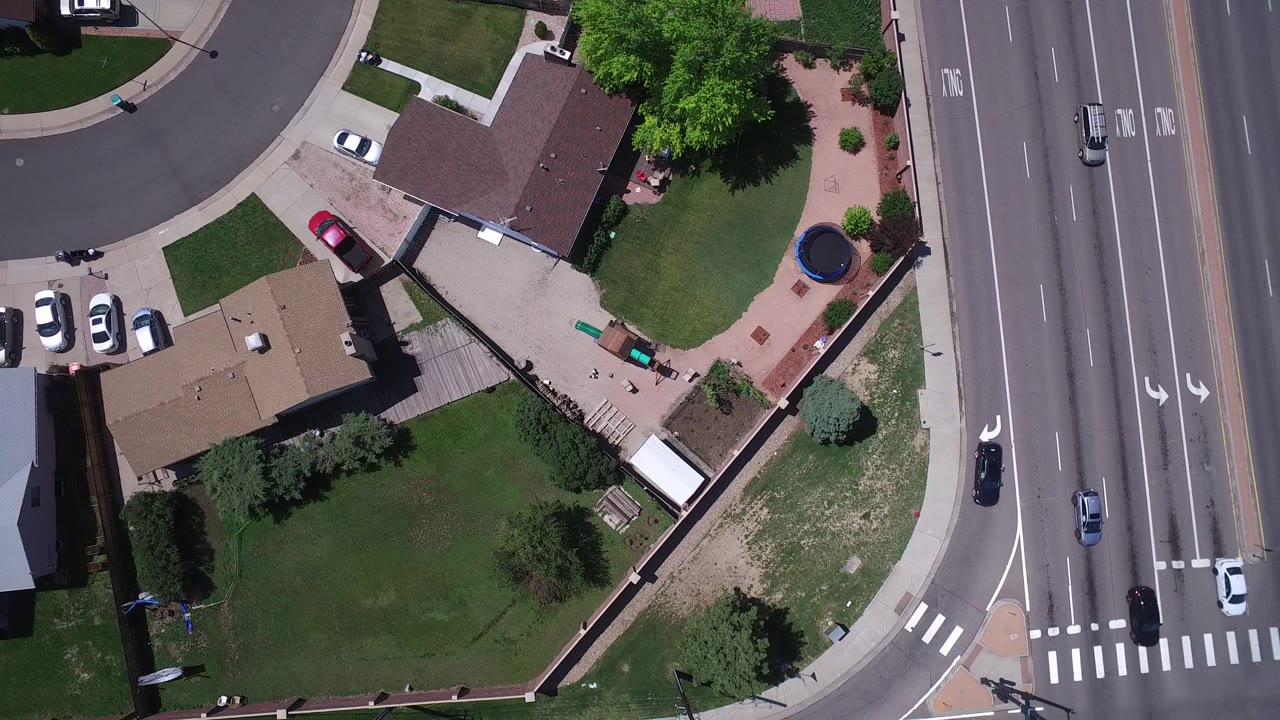 Top-down view of lawns, fences, rooftops, and a road intersection.