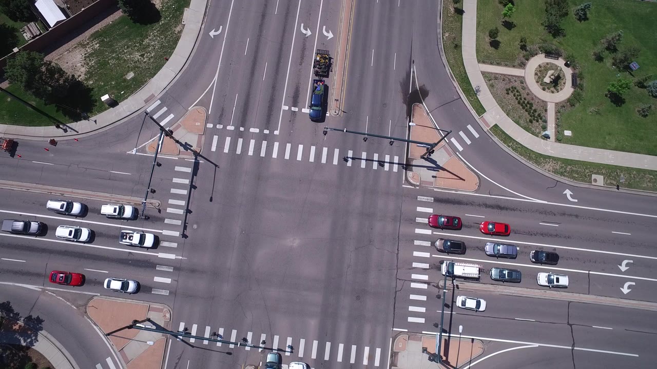 Overhead view of a multi-lane intersection with cars and zebra crossings.