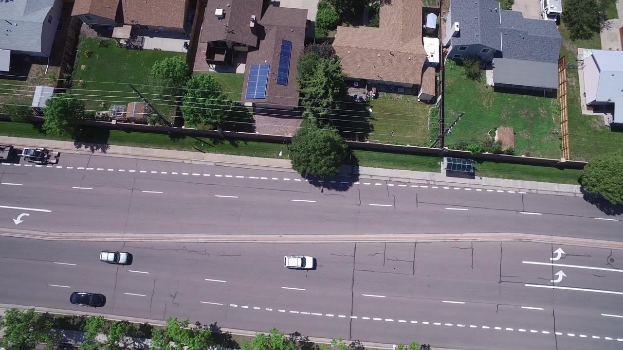 Top-down road traffic with houses, trees, and a marked turn lane