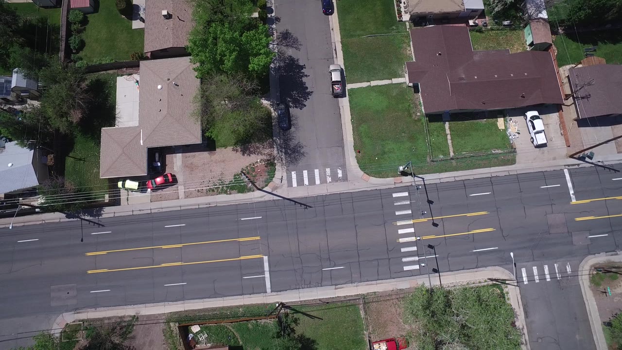 Top-down road crossing with houses and parked cars