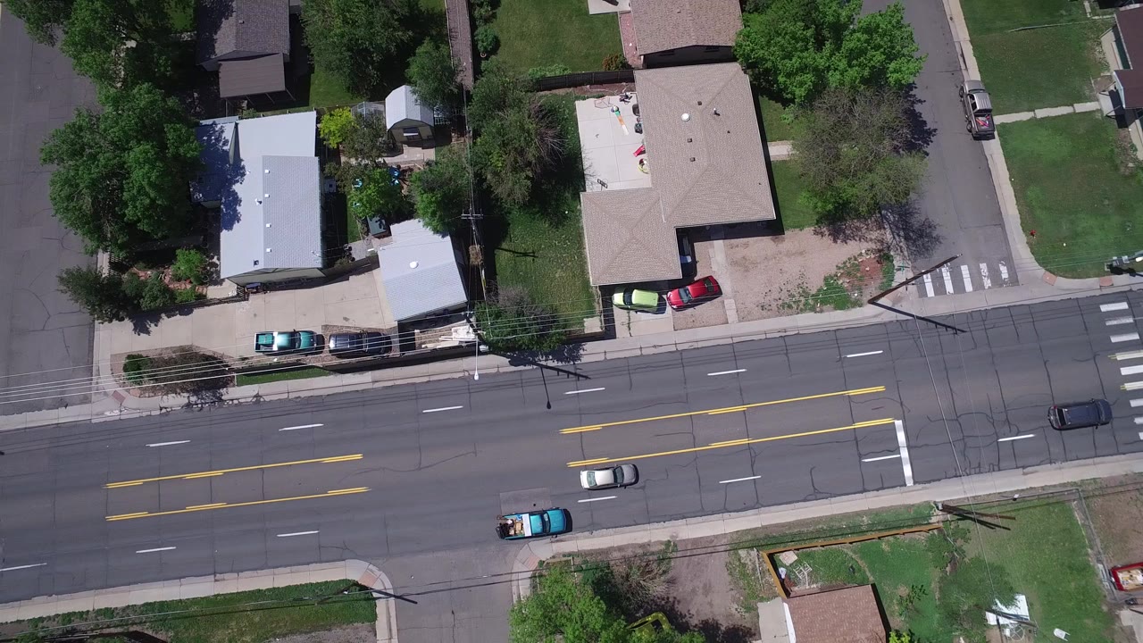 Overhead view of a residential road with cars and houses.