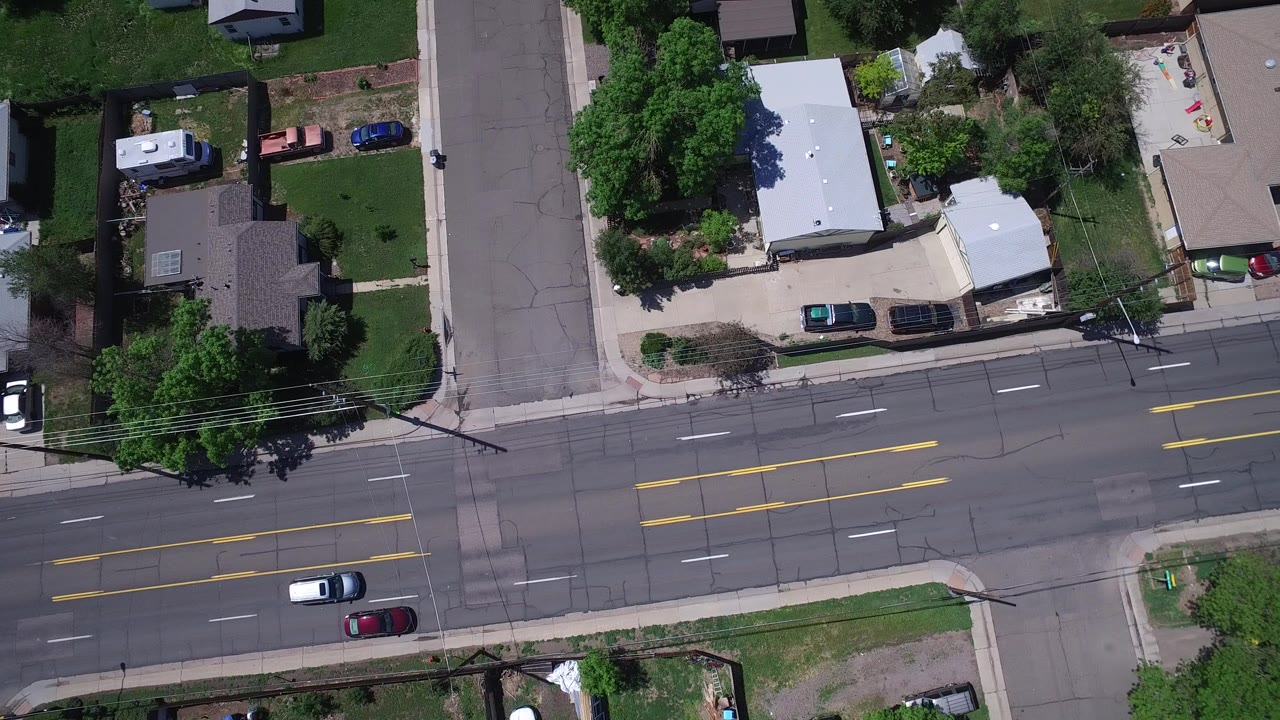 Overhead view of a suburban intersection with homes, lawns, and cars.