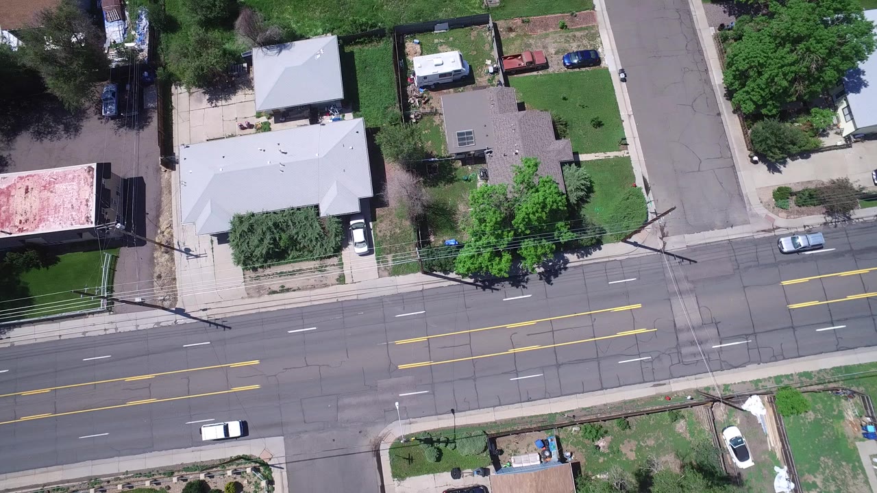 Overhead view of a multi-lane road beside homes and trees.