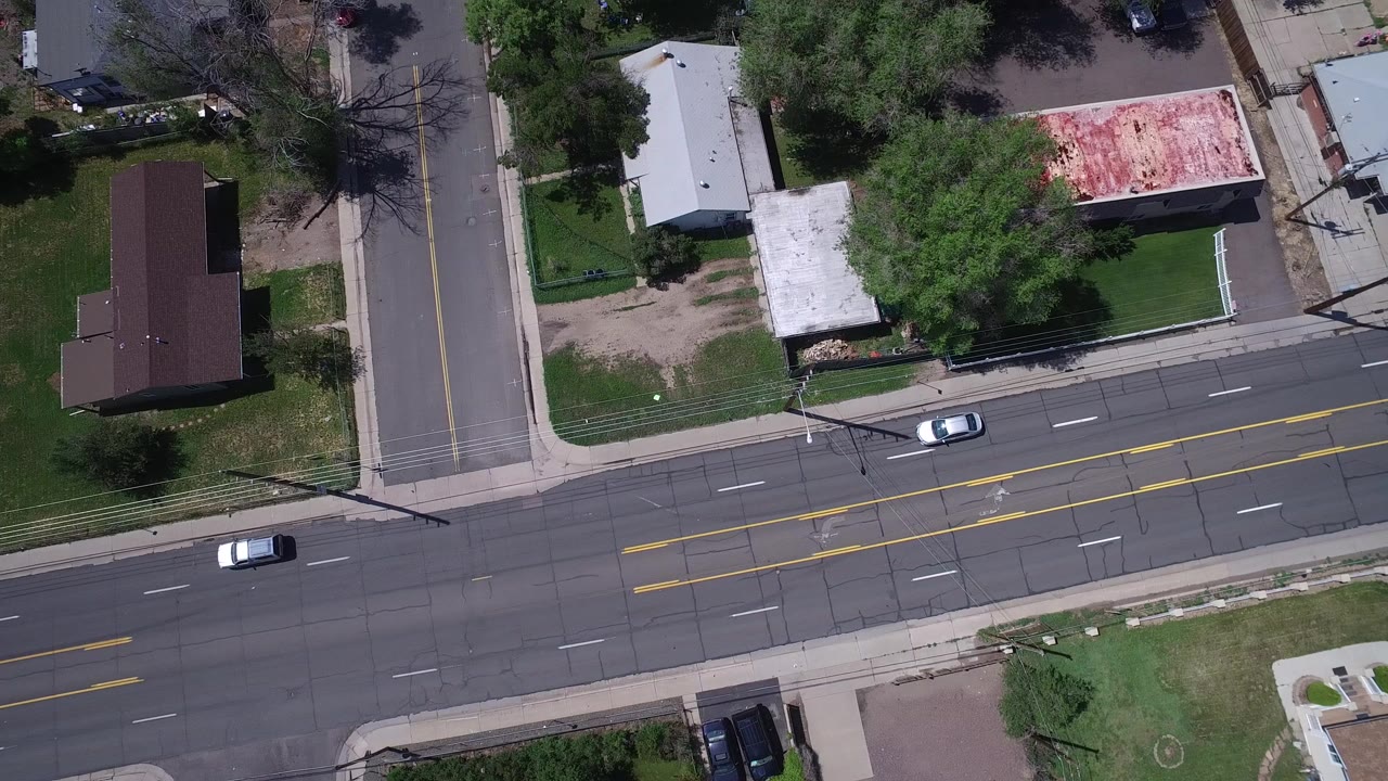 Overhead view of a suburban road junction with houses and lawns.