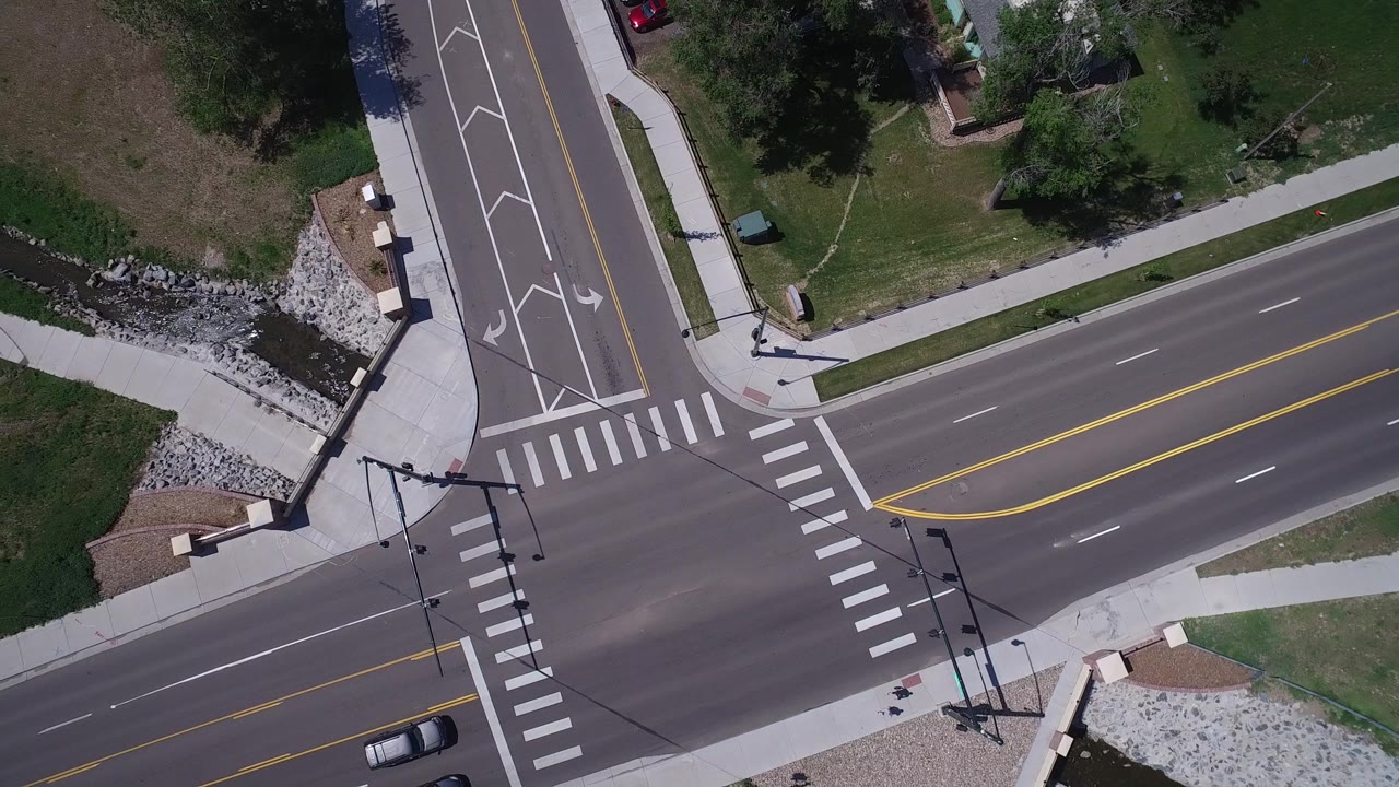 Top-down view of the Westminster junction one second in, with the canal and rock-lined bank above the roads and cars moving through the lower edge, with no visible people.
