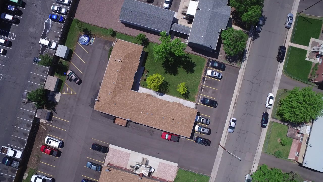 Overhead view of houses, parking lots, streets, trees, and cars.