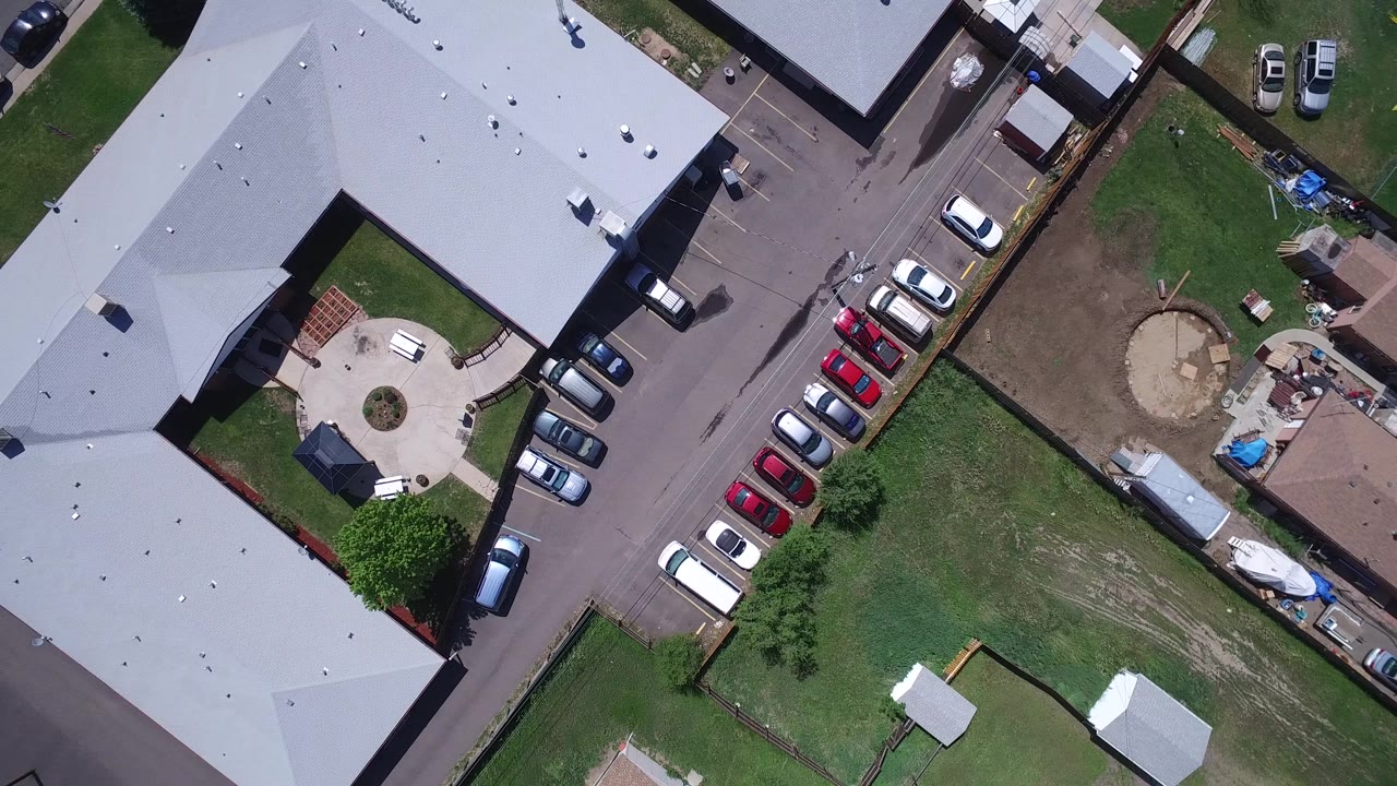 A near-vertical aerial frame over Westminster, Colorado centers on parked cars between pale roofs, fenced grass lots, and a round backyard patio area with no visible people.
