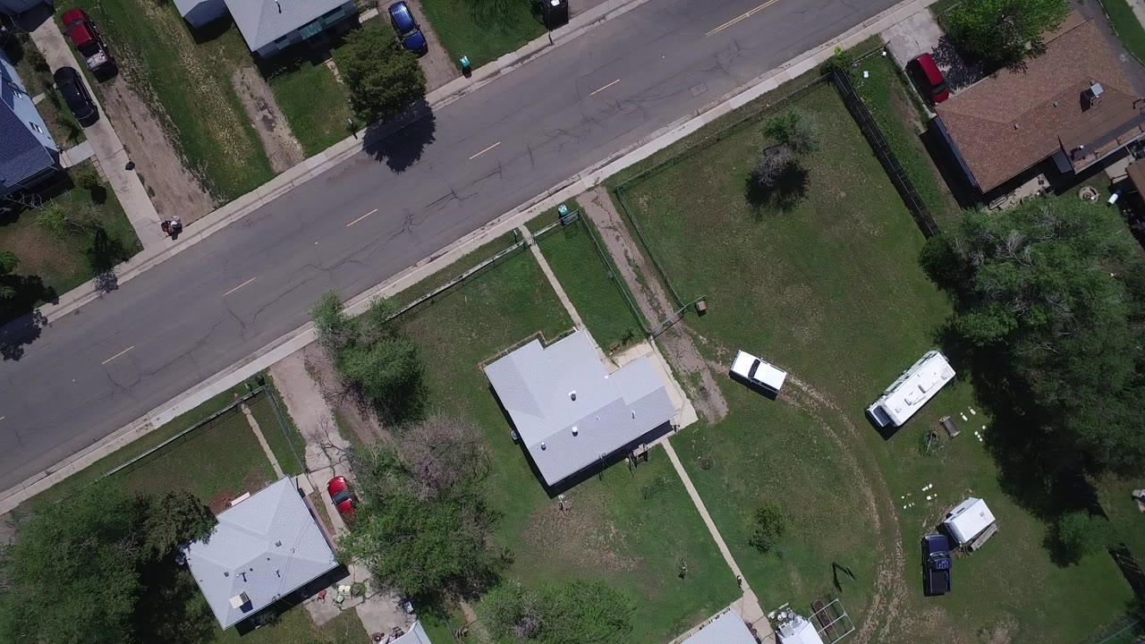 Top-down aerial view of houses, lawns, sidewalks, and a residential street.