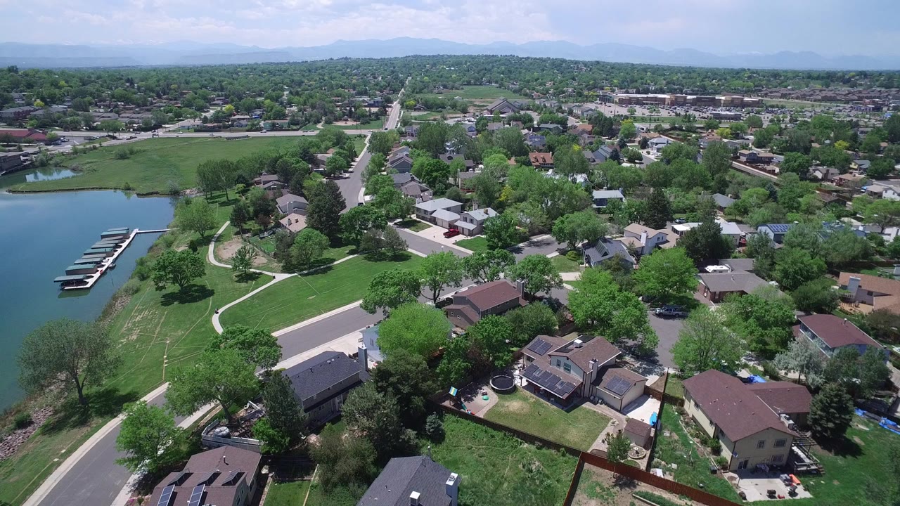 Aerial view of suburban homes beside a lake and green parkland.