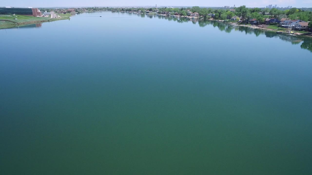 Wide lake with houses and trees along the far shoreline.