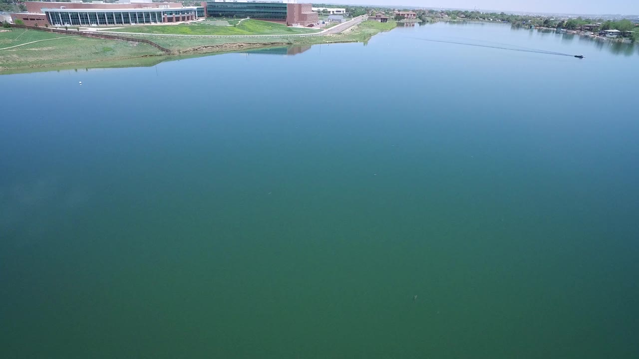Westminster, Colorado aerial view with the water filling most of the frame and the shoreline building held near the top edge, with no recognizable people visible.