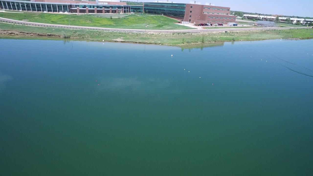 Lake surface with faint underwater color shifts and buildings along the far shore.