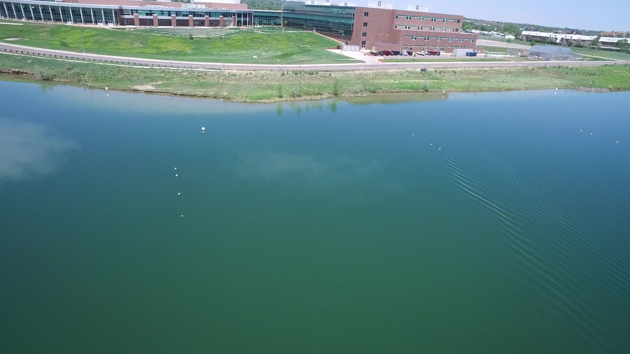 Aerial water surface with diagonal ripple lines and distant buildings.