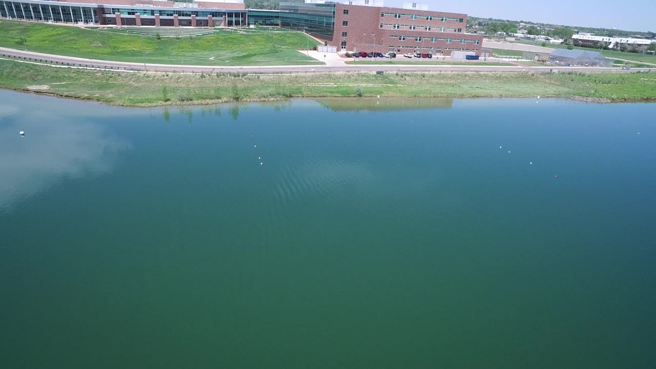 Lake surface with small ripples below a road and brick building