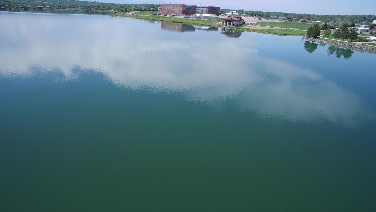 Wide lake view with clouds mirrored in the water and buildings beyond shore