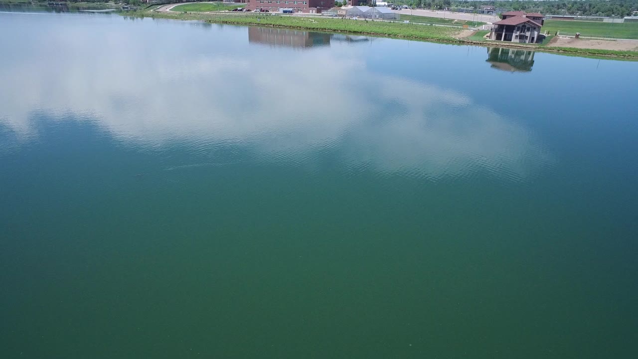 Green-blue water with cloud reflections and a developed shoreline at the top edge.