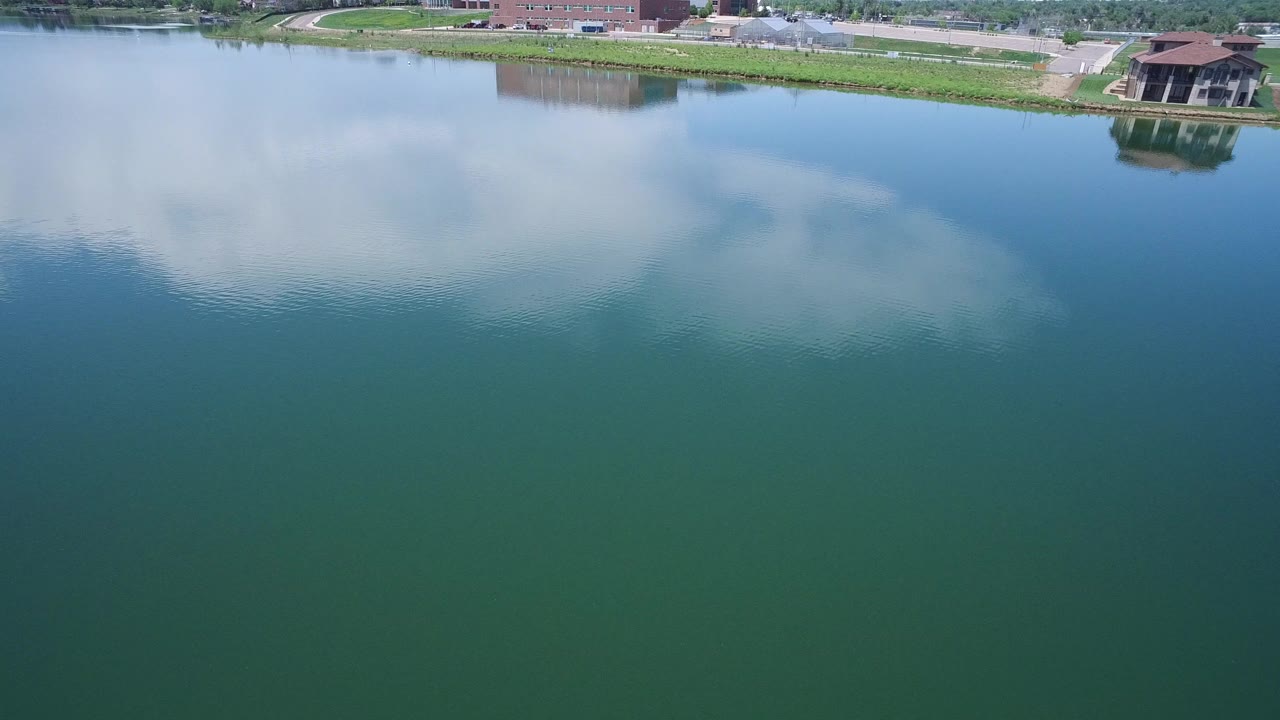 Blue-green water with cloud reflection and a narrow riverbank at the top.