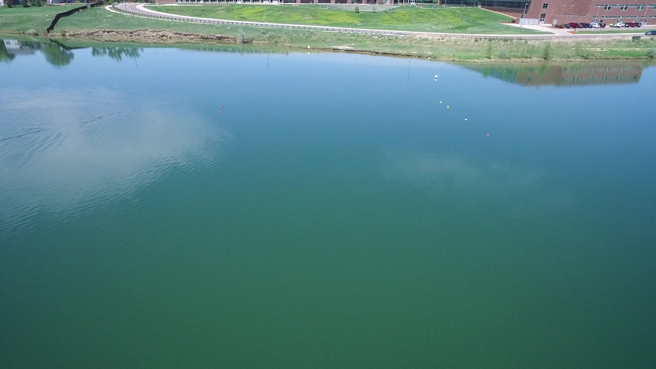 Blue-green water beside a grassy bank and curving road