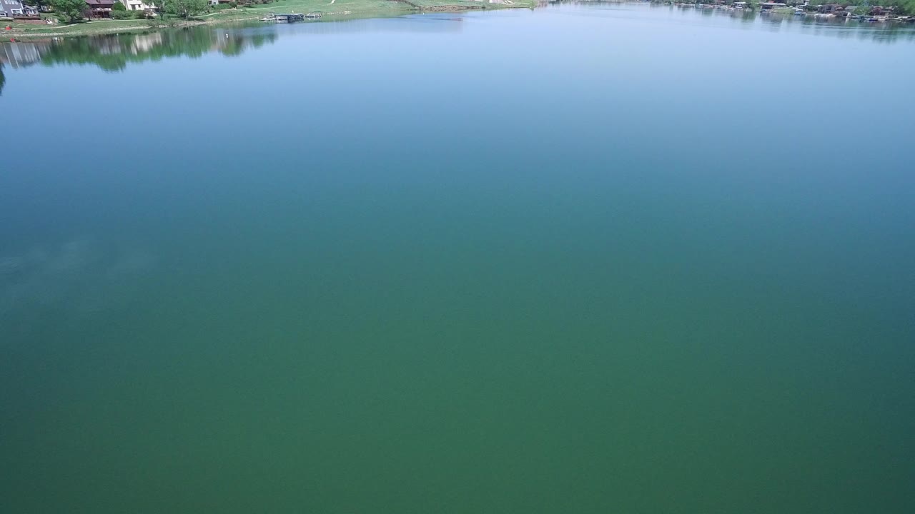 Aerial view over green-blue rippling water with a thin shoreline at the top.