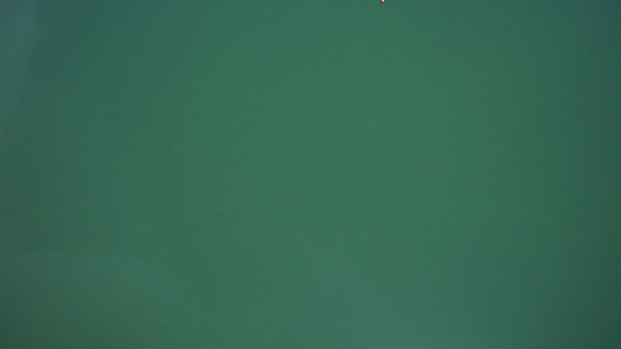 Opening frame from Westminster, Colorado footage showing a uniform green field with a faint bright speck near the top edge and no visible people.
