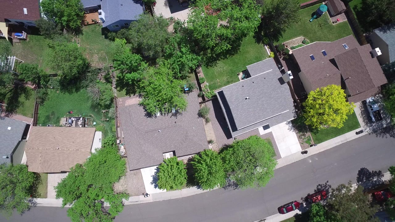 Top-down view of houses along a curved street with trees and driveways.