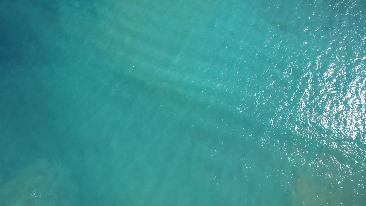 Overhead view of turquoise water in Playita, Baja California Sur with sunlit ripples and no visible people.