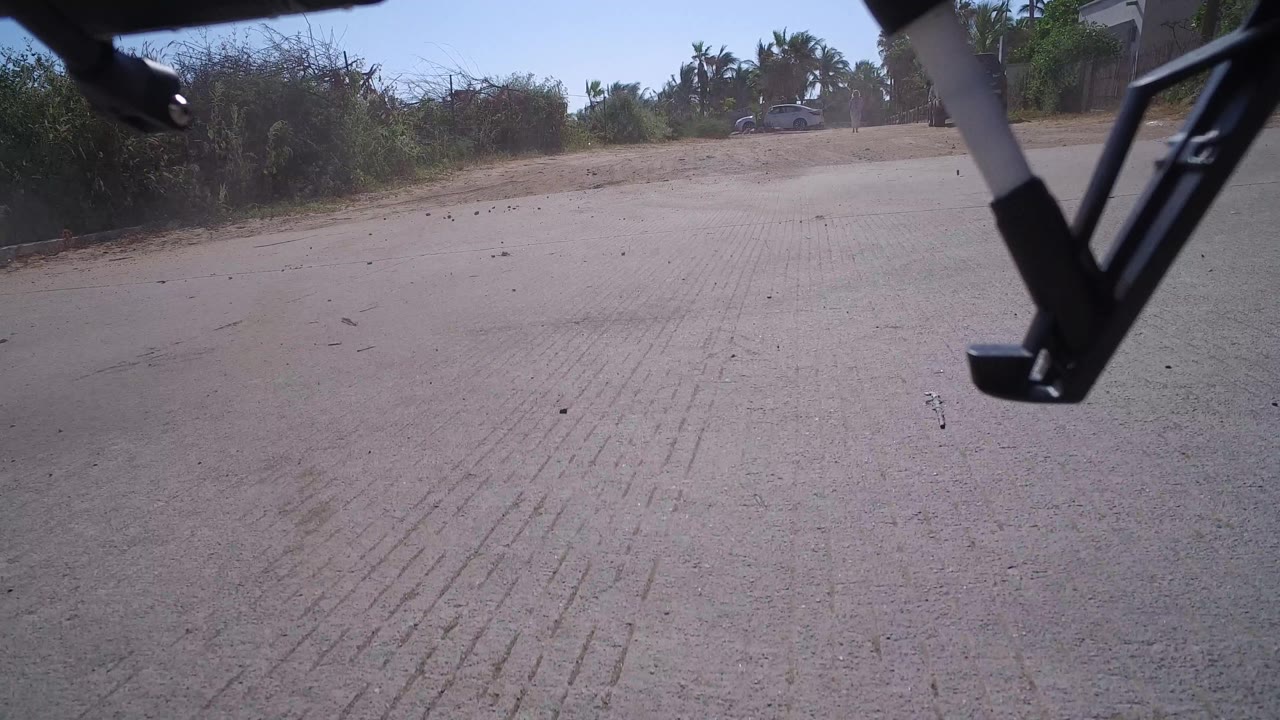 Drone landing gear closer to the road surface on a sunny street.