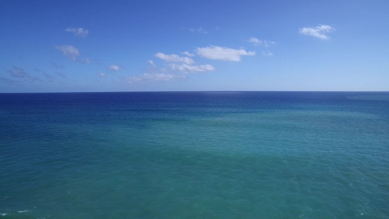 Open sea with gentle ripples below scattered clouds