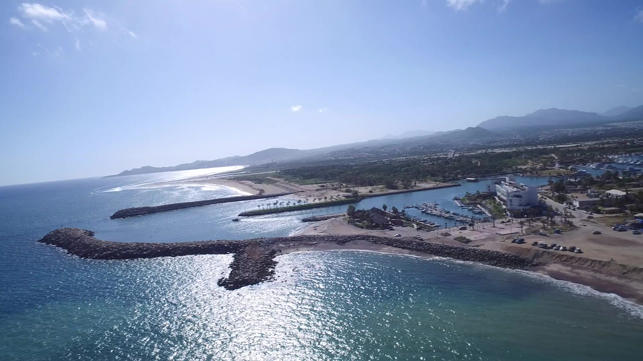 Aerial coastline with ocean, beach, harbor, and rock breakwaters