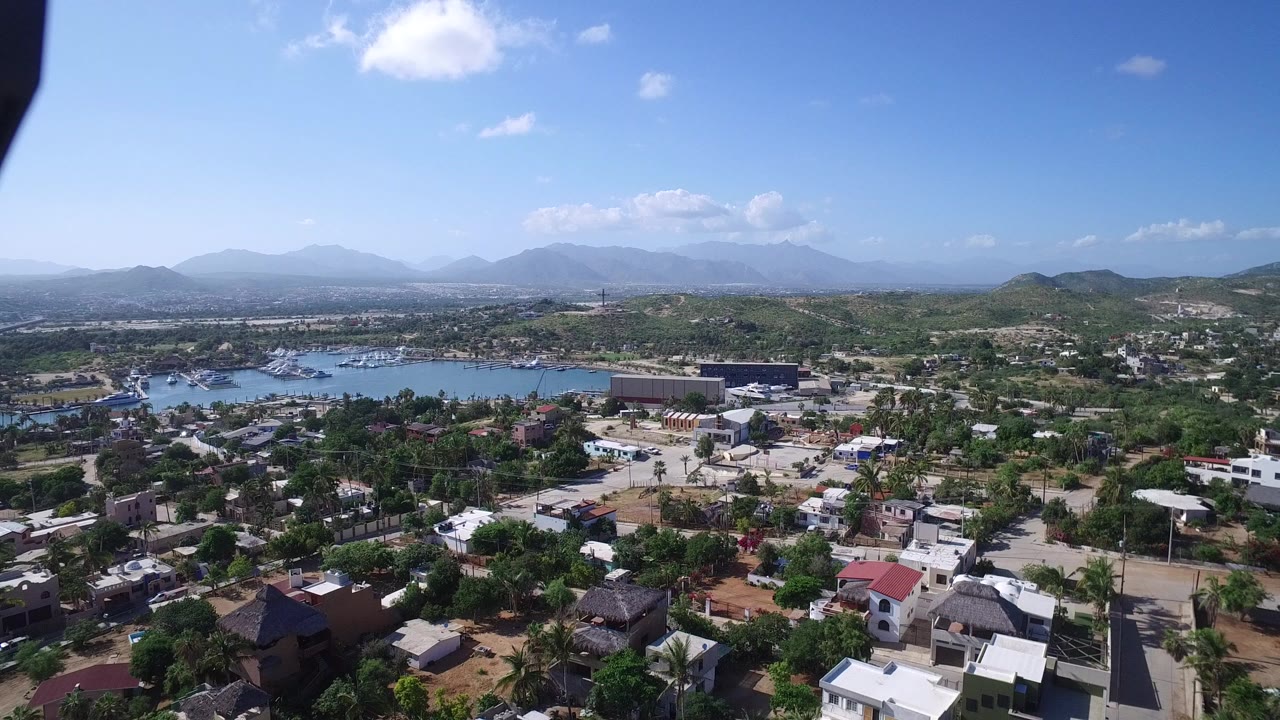 Aerial view of homes, trees, water, hills, and distant mountains.