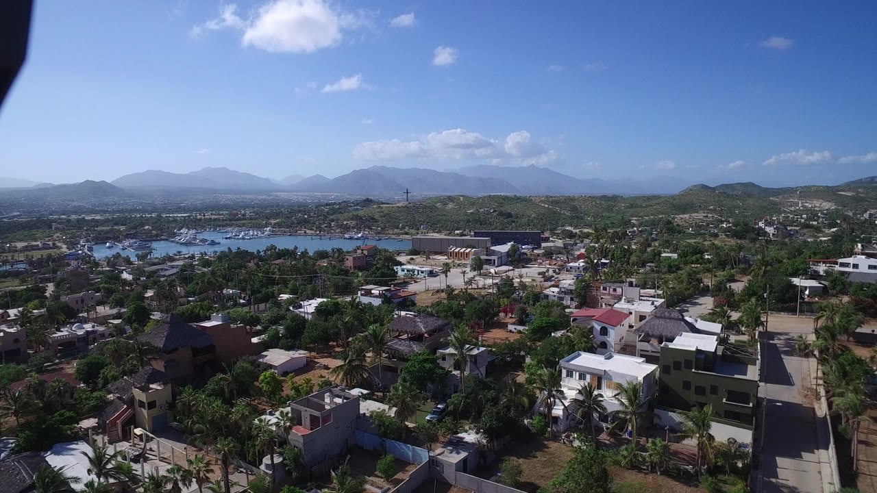 Aerial view over houses, palms, water, and distant mountains
