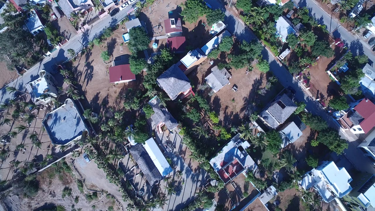 Overhead view of houses, roads, trees, and walled yards.