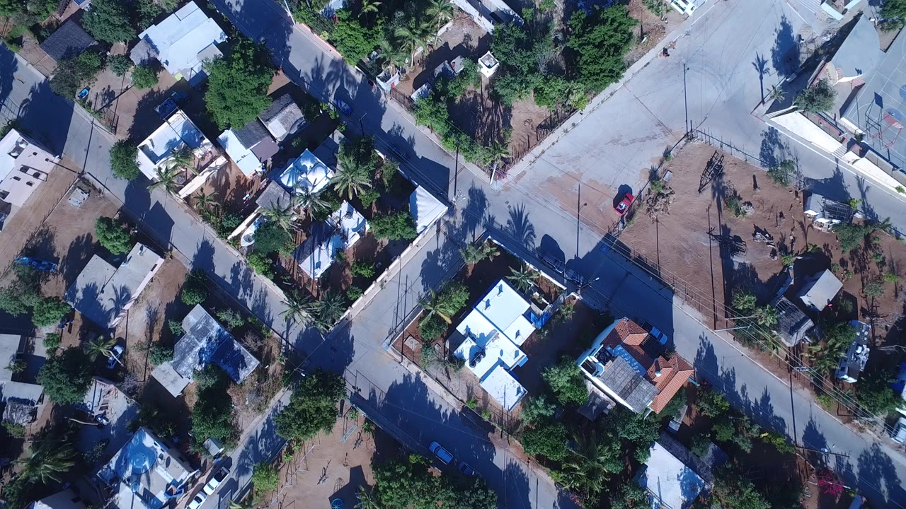 Overhead view of houses, trees, and intersecting concrete roads.