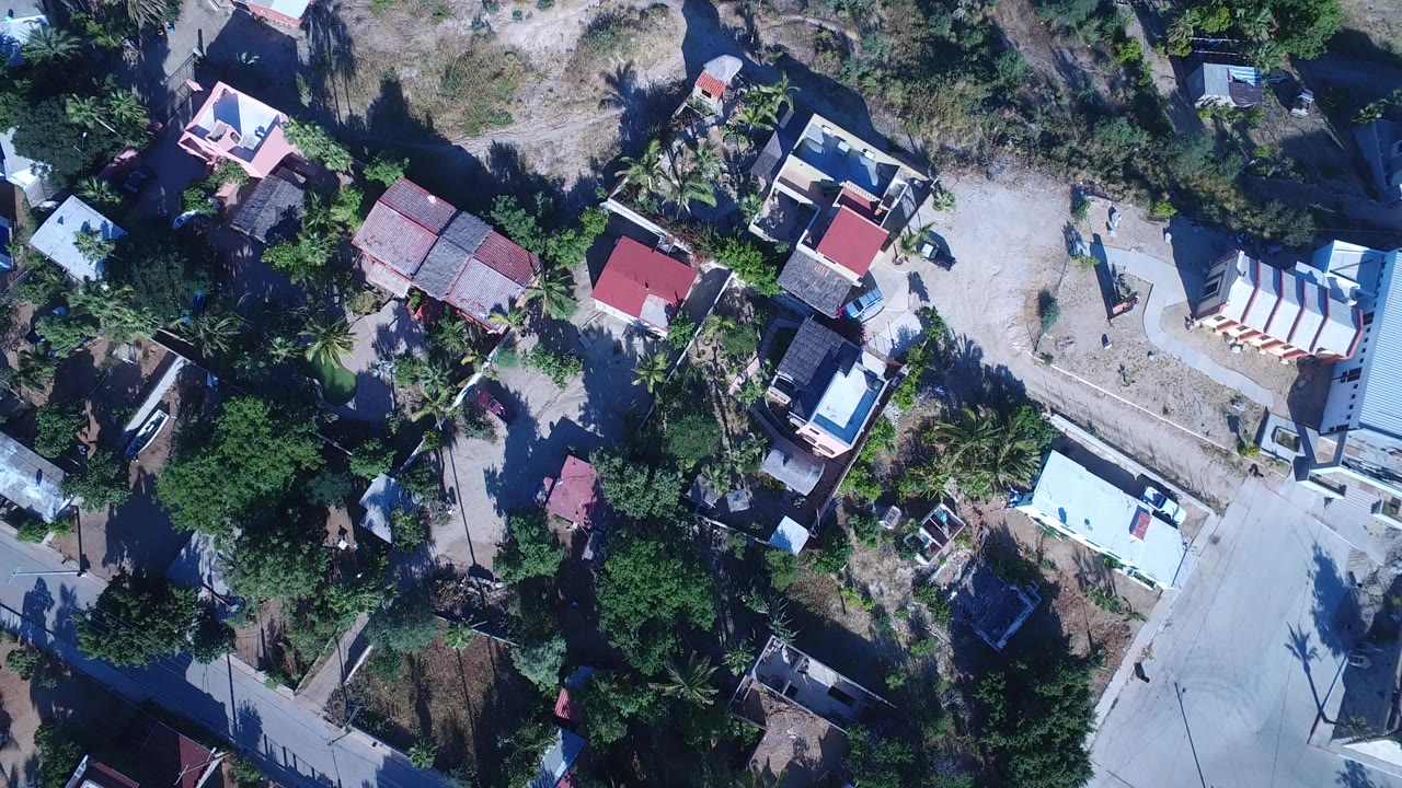 Overhead aerial view of homes, dirt roads, trees, and dry lots.