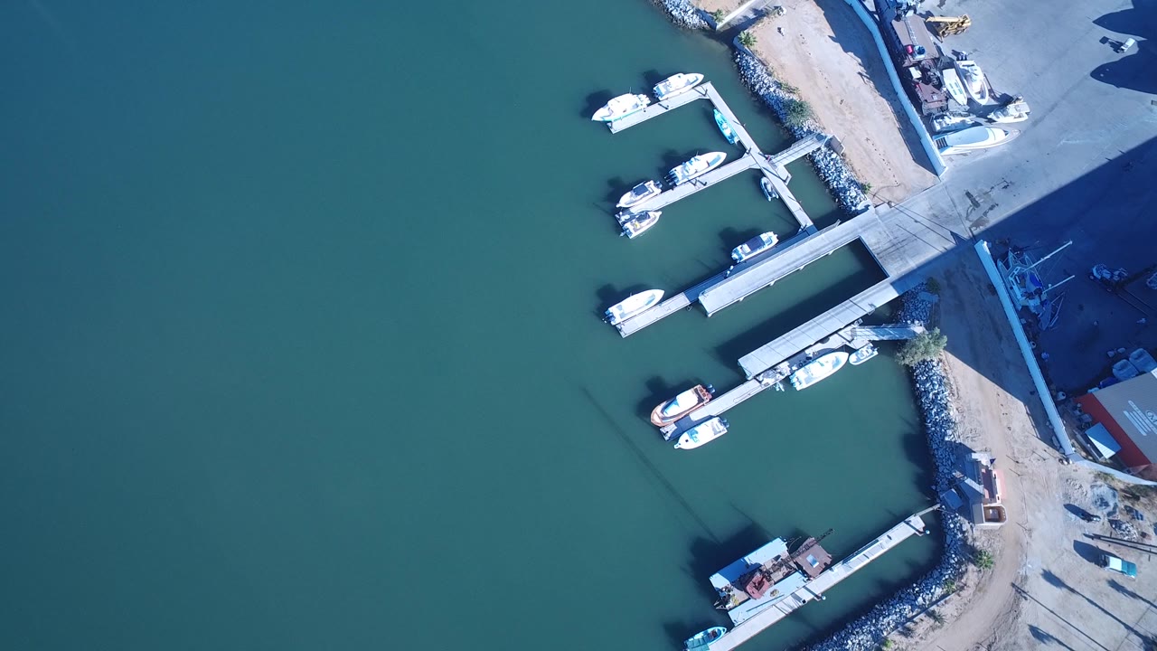 Drone view of docks, boats, and a harbor work area.