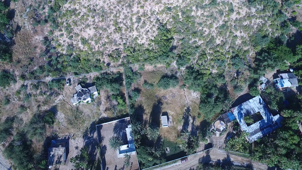 Overhead drone view of scrub vegetation and scattered houses.